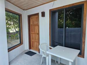 a white table and chairs on a porch with a door at Sunset Beach View in Dhangethi