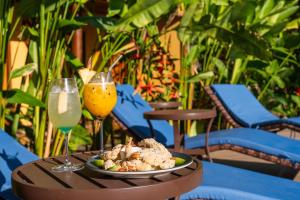 a table with a plate of food and two glasses of drinks at Pousada Pedra Torta in Itacaré