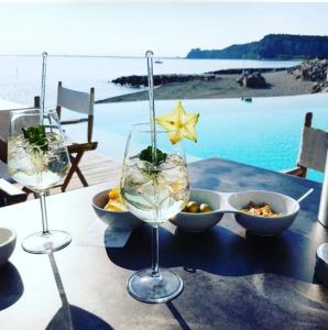 a table with two wine glasses and a bowl of food at Portopiccolo Avolare Apartments in Borgo, beach included in Sistiana