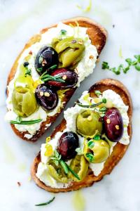 two pieces of toast with olives and cheese on a plate at Eman Resort & Villas in Ulcinj