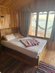 a bed in a room with a large window at Love beach camp in Taba