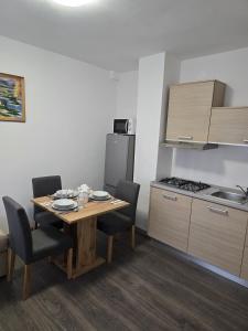 a kitchen with a table and chairs and a kitchen with a refrigerator at Apartment BRIG in Kamenica Skradnička