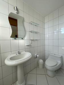 a white bathroom with a sink and a toilet at HOSPEDAJE LAS FLORES ICA in Ica