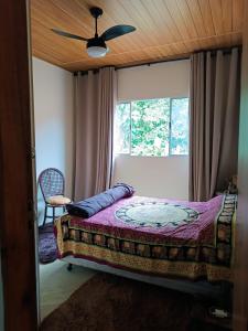 a bedroom with a bed with a ceiling fan and a window at ALOHA#Sossego in Ubatuba