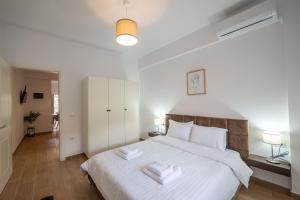 a bedroom with a large white bed with two towels at Philoxenia Apartments Saranda in Sarandë