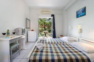 a bedroom with a bed and a desk and a window at Hotel Athina in Karavomylos