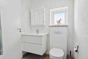 a white bathroom with a sink and a toilet at Lovely Bright House Near The Beach In Nature in Ørsted +17 photos