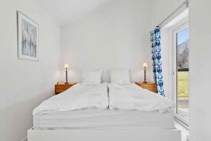 a white bed in a white bedroom with a window at Lovely Bright House Near The Beach In Nature in Ørsted