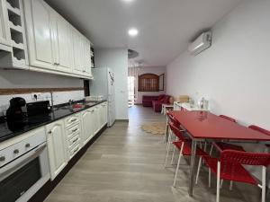 a kitchen with white cabinets and a table with red chairs at El colibri puerto de mazarron in Puerto de Mazarrón