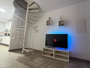 a living room with a television and a spiral staircase at El colibri puerto de mazarron in Puerto de Mazarrón
