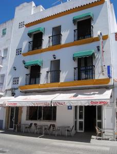 un edificio blanco con mesas y sillas delante en Hostal Malia, en Conil de la Frontera