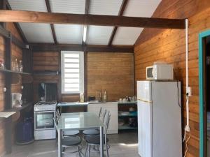 a kitchen with a table and a refrigerator in it at Bungalow ROUGE GITES PASSION in Capesterre-Belle-Eau