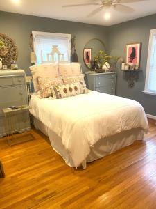 een slaapkamer met een bed met witte lakens en houten vloeren bij A beautiful award winning bungalow in Indianapolis
