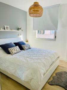 Un dormitorio con una gran cama blanca con almohadas azules. en Esti Chill & Stay, en Corralejo