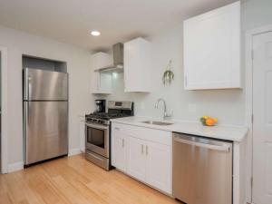 a kitchen with white cabinets and a stainless steel refrigerator at Jennifer's Historic College Hill Apartment - The Lookout in Providence