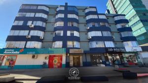 a large blue building with windows on a street at Apto no centro de Torres | Aceita Pet in Torres