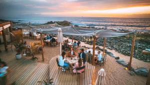 Un grupo de personas sentadas en mesas en la playa. en Apartamento de lujo en Residencial El Mocan, en Palm-mar