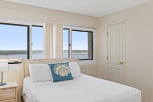 une chambre avec un lit avec des draps blancs et des fenêtres dans l'établissement Pinnacle Port A-701, à Carillon Beach