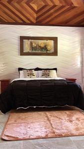 a large bed with a black comforter in a bedroom at Chalé da leila in Bocaina de Minas