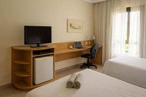 um quarto de hotel com uma escrivaninha com uma TV e uma cama em ELEGANCE SUÍTES FRANCA em Franca