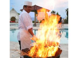 Ein Mann, der Essen über einem Grill mit Flammen kocht. in der Unterkunft Umibe no Kajuen - Vacation STAY 17476v in Konan
