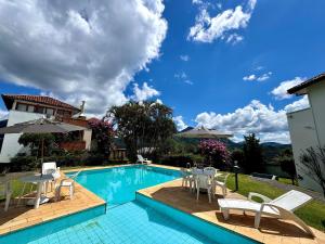 a swimming pool with chairs and umbrellas next to a house at Duplex incrível a 5 min do centro com piscina in Nova Friburgo