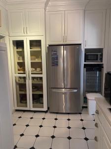 a kitchen with white cabinets and a stainless steel refrigerator at Beautiful Villa by the Beach in Nassau