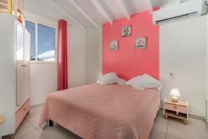 ein Schlafzimmer mit einem Bett und einer roten Wand in der Unterkunft Villa Gosier T3- Vue Nature - Romantique in Le Gosier
