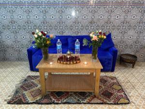 niebieska kanapa z 2 butelkami wody i stół z kwiatami w obiekcie Red Vibes Hostel Marrakech w Marakeszu