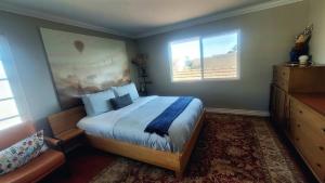 a bedroom with a large bed and two windows at Coastal Retreat Home 2 miles from Beach in Huntington Beach