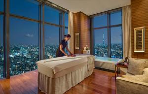 a man making a bed in a room with a view at Mandarin Oriental, Tokyo in Tokyo