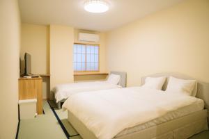 a room with two beds and a television in it at Matsuya hotel in Myoko