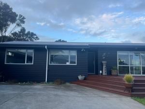 a blue house with a wooden deck at RAGLAN - FULLY self contained 1 bedroom in Raglan +1 photo