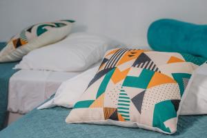 two beds with colorful pillows on top of them at La Posada del Buzo in Colón