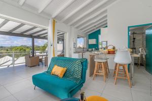 a living room with a blue couch and a kitchen at La villa montobanez in Le Gosier
