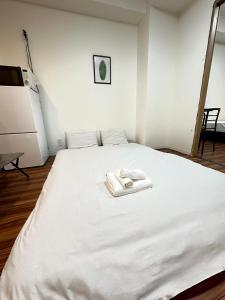ein weißes Bett mit zwei Handtüchern darauf in der Unterkunft SOLASIA residence 北上野401 in Tokio