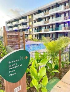 a sign in front of a building with a swimming pool at Loft Mana Experience INN in Ipojuca