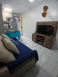 a living room with a couch and a flat screen tv at Flat Monte Castelo - Gravatá - Até 5 pessoas, próximo da área de lazer in Sairé