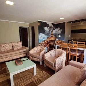 a living room with a couch and chairs and a painting at Departamento Caseros Centro in Salta +80 photos