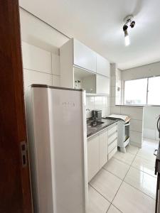 a kitchen with white cabinets and a refrigerator at Apto próximo Ufu, Parque do Sabia, Madrecor in Uberlândia +53 photos