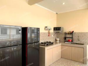 une cuisine avec un réfrigérateur noir et une cuisinière dans l'établissement Premium Guest House Harmoni Jakarta pusat - Free Wifi & Smart tv Facility, à Jakarta