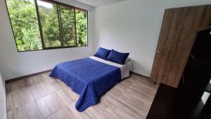 a bedroom with a bed with blue sheets and a window at Eco Retiro La Paz in Vergara