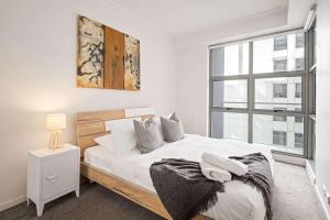 Un dormitorio blanco con una cama grande y una ventana. en Cozy 2BR Apartment Steps from Darling Harbour, en Sídney