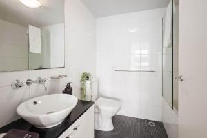 Un baño blanco con lavabo e inodoro. en Cozy 2BR Apartment Steps from Darling Harbour, en Sídney