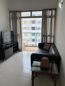 a living room with a couch and a large window at Apartamento Guarujá Pitangueiras in Guarujá