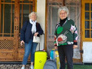 two older women standing in front of a door with their luggage at Reshi guest house in Srinagar