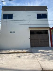ein weißes Gebäude mit einer Garage mit einer Tür in der Unterkunft Departamento Rosedal 3 in Oaxtepec