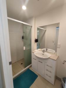 Un baño con lavabo y ducha con espejo. en 3 Double Beds and 1 Single Bed and 2 Double Sofa Beds in a small 2 Bedrooms Penthouse, en Auckland