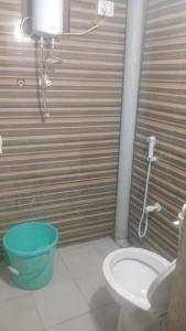 a bathroom with a toilet and a blue bucket at Raj Rajeswari sadan in Ayodhya