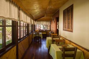 a dining room with tables and chairs and windows at Pousada da Carmem in Visconde De Maua